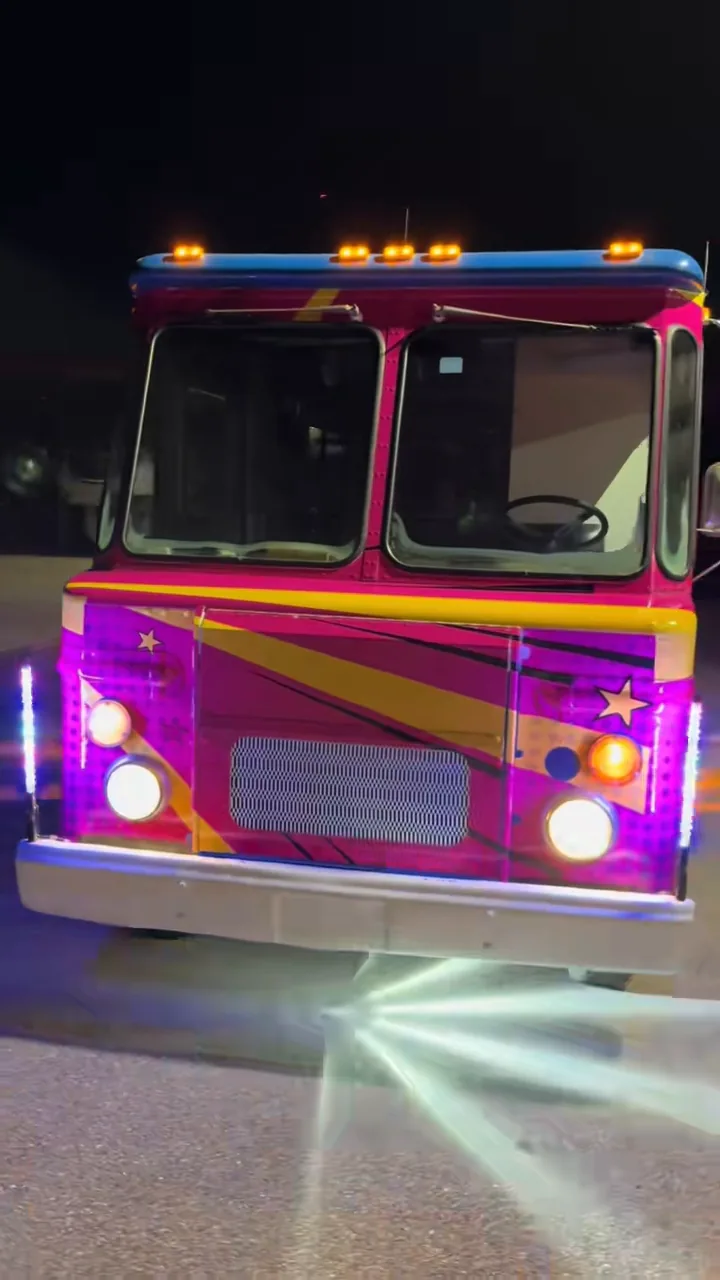 Wrapped food truck at night with a white radial light pattern on the pavement.