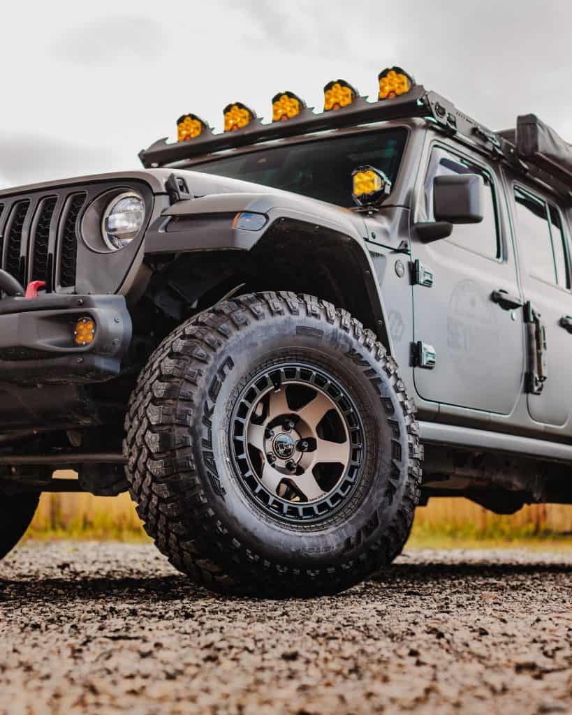 Black off-road Jeep with rugged tires and LED light bar on top.