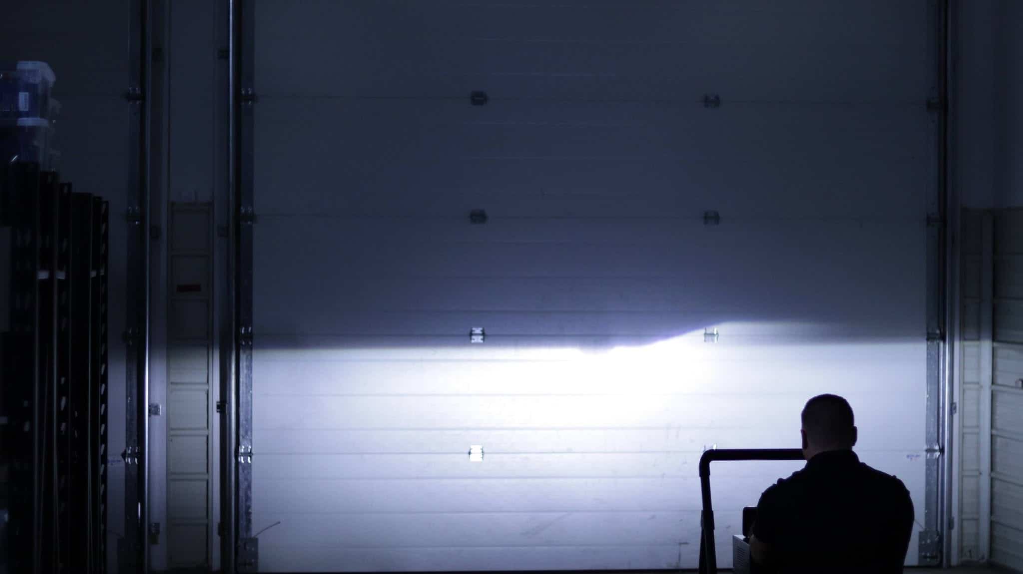Headlight beam across a garage door with a stepped cutoff in BTS Lighting's comparison