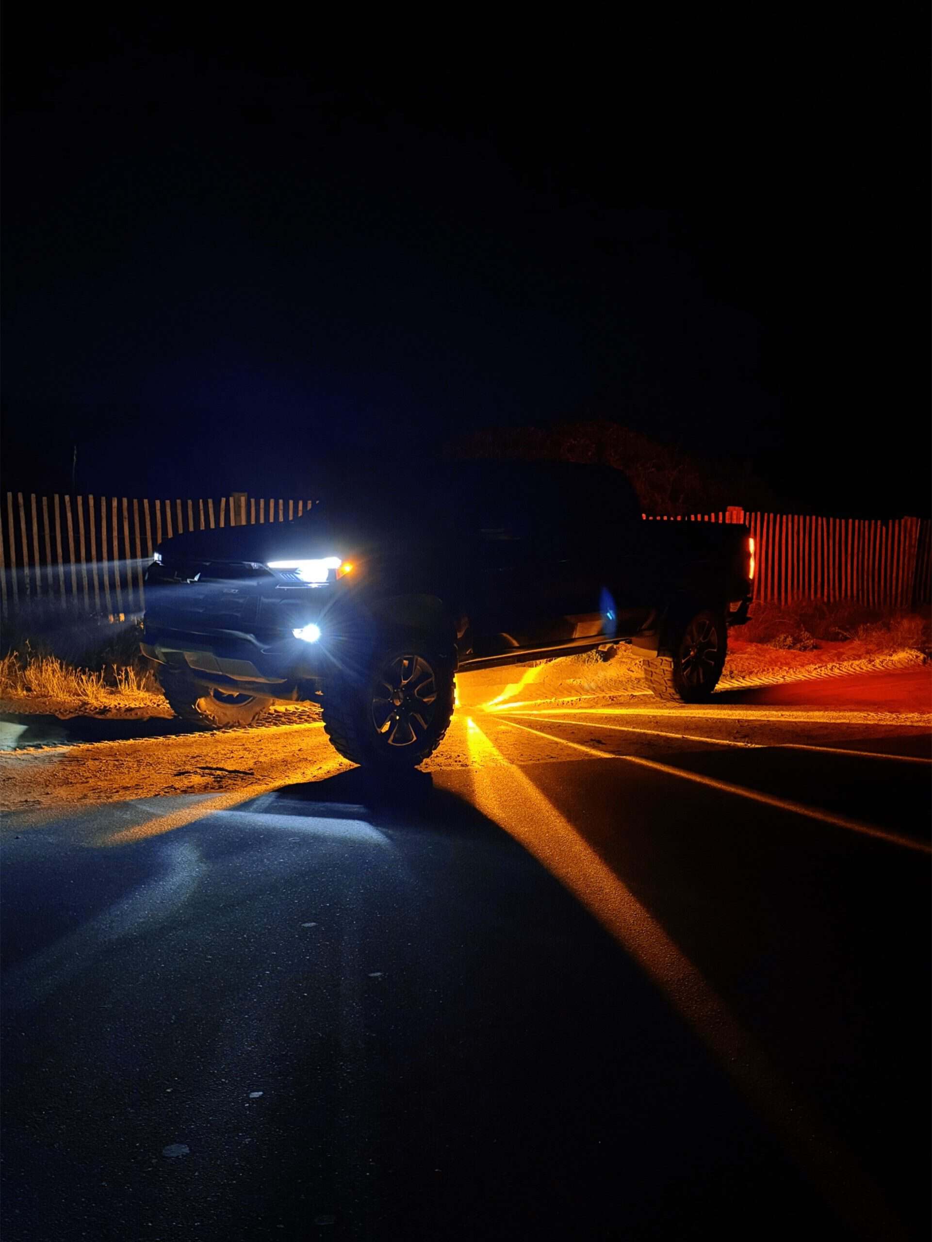 Black lifted pickup with amber Glass Is Class light patterns beneath the truck