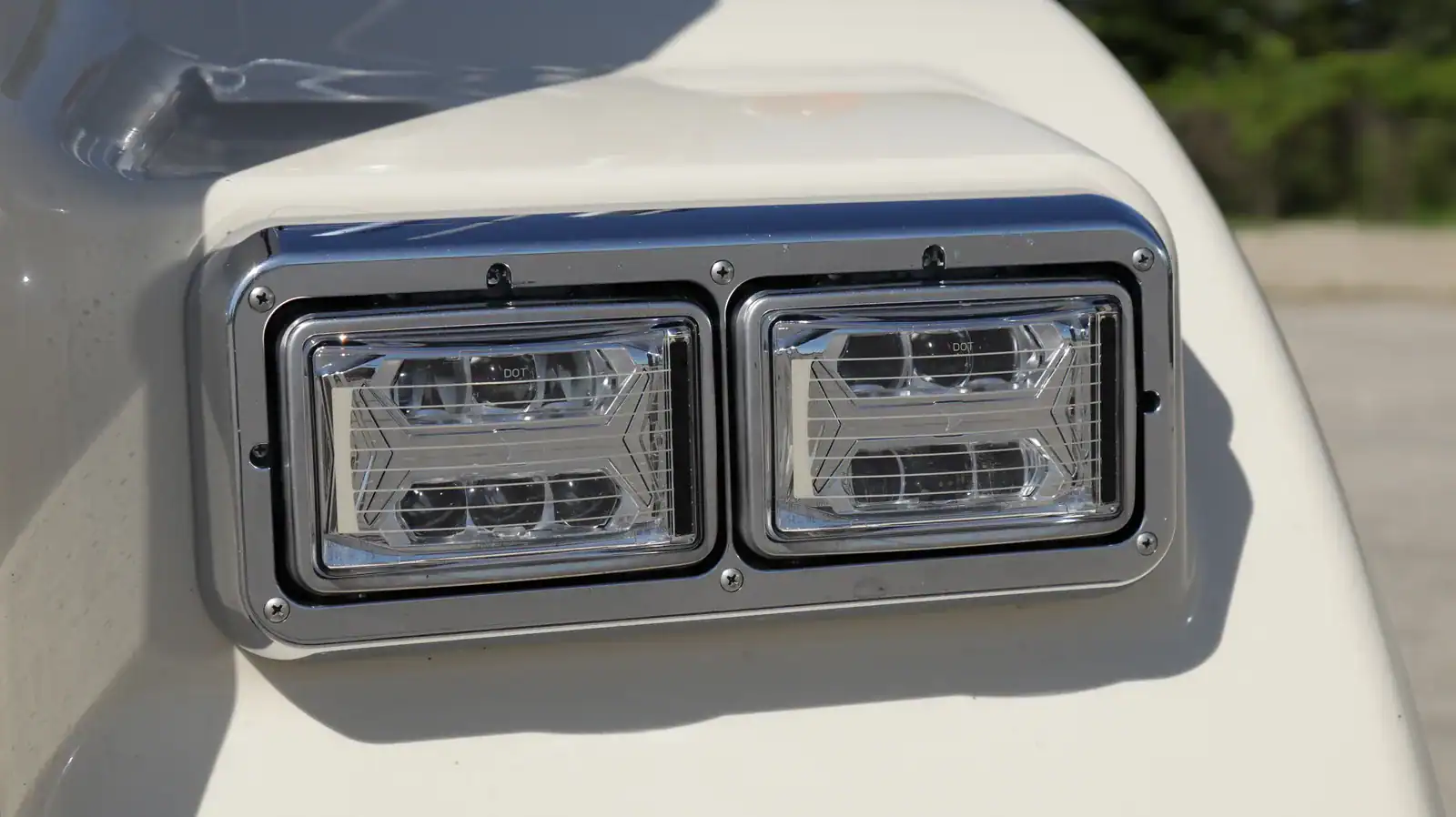 Close-up of two chrome J.W. Speaker EVO-X rectangular headlights with X-shaped optics on the cream Kenworth