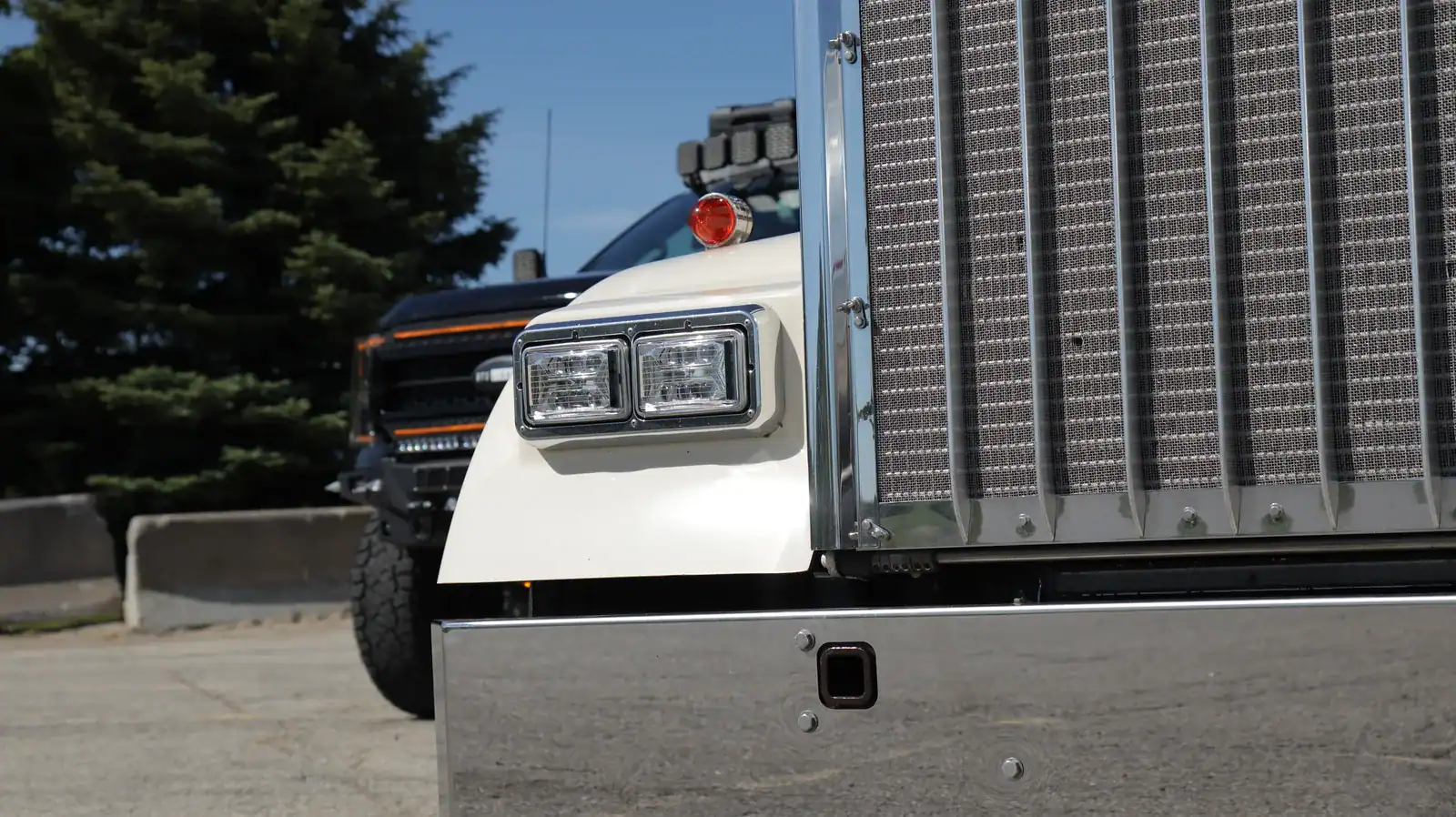 Chrome EVO-X headlight pair beside the grille of a cream Kenworth W900L