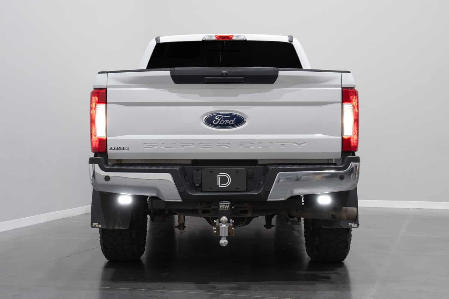 Diode Dynamics SSC2 white reverse lights installed below a Ford Super Duty rear bumper